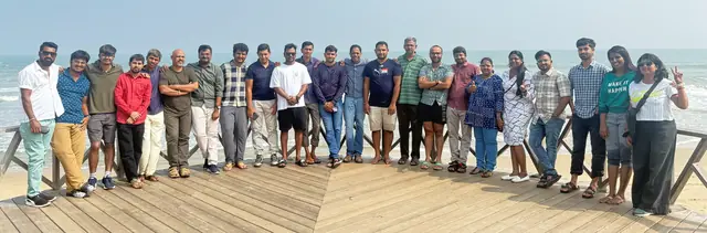 The team standing in one long line on a boardwalk by the sea