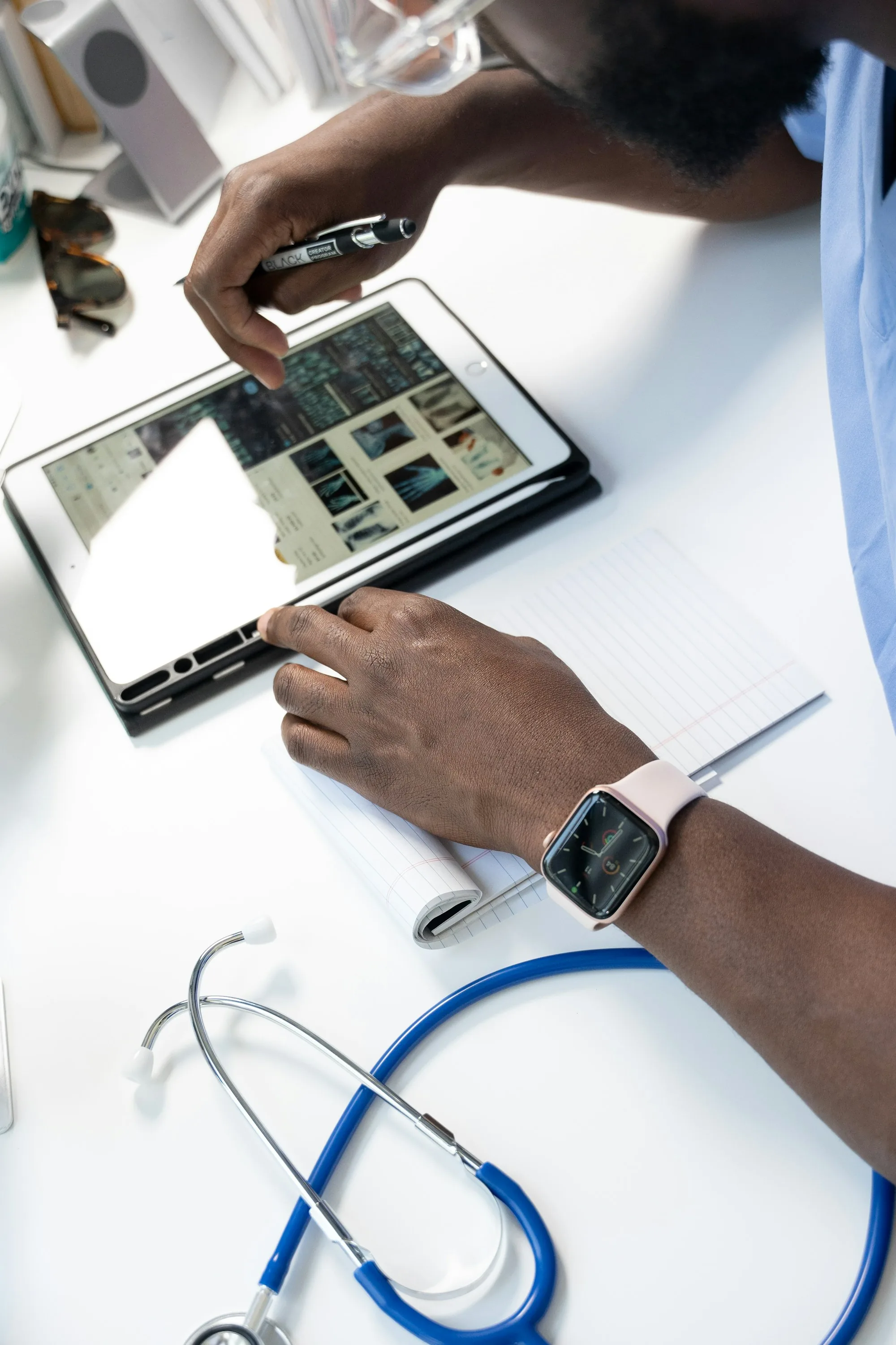 A clinician’s hands reviewing scan images on a tablet beside a stethoscope