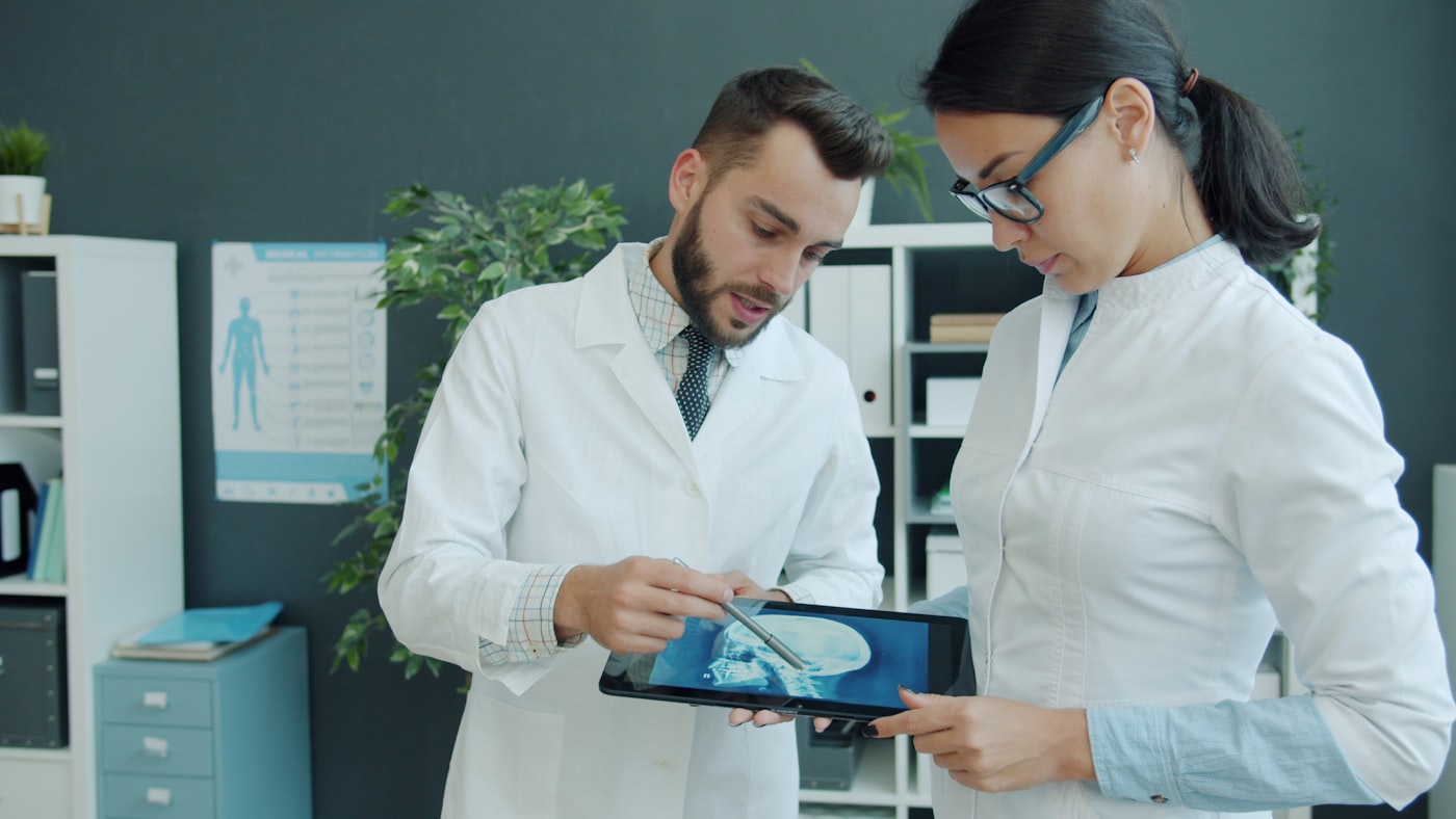 Two clinicians in white coats reviewing a scan together on a tablet